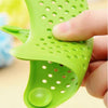 Green silicone star sink strainer and hair catcher with suction cups held by hand for shower or kitchen drain.