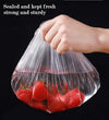Disposable elastic food storage covers holding fresh tomatoes. Transparent stretch lids for airtight kitchen preservation.