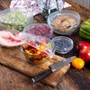 Elastic disposable cling film bowl covers used to seal fresh fruits and food in kitchen storage containers.