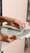 Waffle pack of 3 kitchen towels drying a sage green ceramic plate for absorbent, textured cleaning.