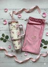 The Stanley X LoveShackFancy Quencher tumbler with bow straw topper and matching pink velvet gift bag.