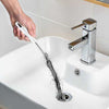 Sink drain cleaning brush removing hair clogs from a bathroom vanity sink for effective pipe maintenance.