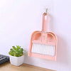 Set of Mini Hand Brush and Dustpan in pink, hanging on a wall for easy desk or keyboard cleaning.