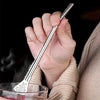 Stainless steel spoon with straw and integrated filter for yerba mate tea in a glass cup.