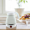 Folding electric kettle made of white silicone, ideal for portable travel use on a kitchen countertop.