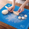 Non-stick silicone baking mat with measurement markings being used to roll out dough with a wooden rolling pin.