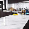 White marble sheet used as a glossy, waterproof adhesive countertop wrap in a modern kitchen with dark cabinets.