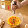 Manual egg beater, stainless steel semi-auto hand whisk mixing eggs in a glass bowl for kitchen cooking.