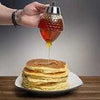 Honey Jar Dispenser pouring fresh golden honey onto a stack of warm pancakes for breakfast.