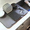 Dish drying mat with rack holding plates and cookware, super absorbent kitchen draining pad on a white countertop.