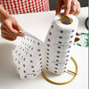 Metal tissue roll stand and heavy-duty vertical paper towel holder with polka dot paper towels on a white table.