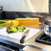 Disposable Cutting Board Mats with sliding cutter and flexible chopping sheets on a kitchen counter with fresh vegetables.