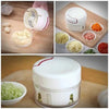 Mini Speedy Garlic & Vegetable Chopper, a manual hand-pull food processor chopping fresh ingredients on a cutting board.