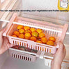 Stretchable fridge organizer basket for adjustable, space-saving kitchen storage of fruits and vegetables.